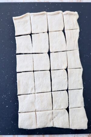 crescent roll dough on cutting board cut into 24 small squares
