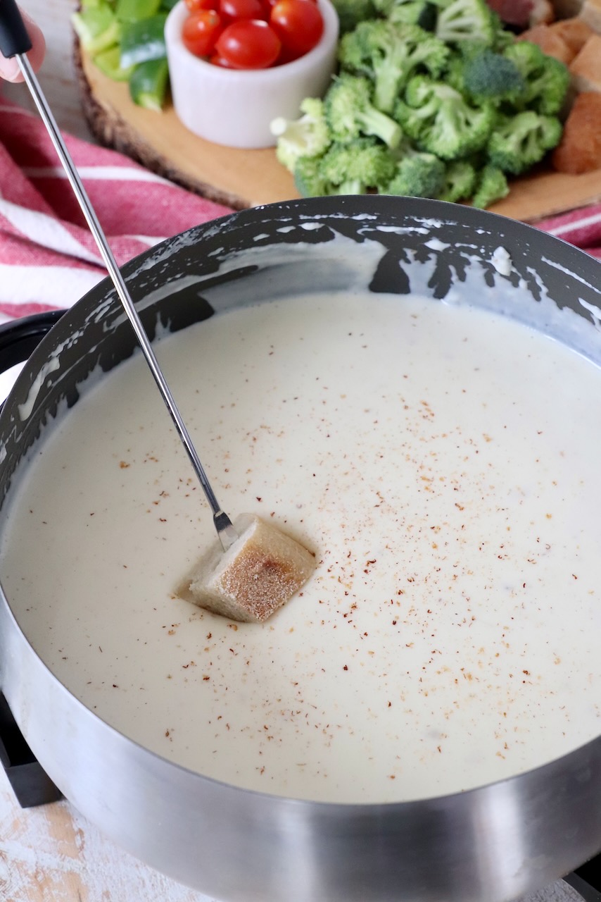 piece of bread dipped into cheese fondue in fondue pot