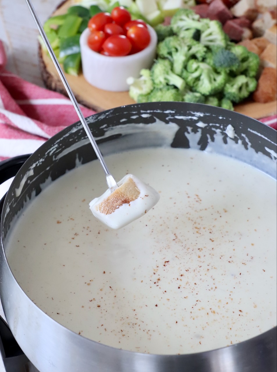 bread dipped into cheese fondue in pot