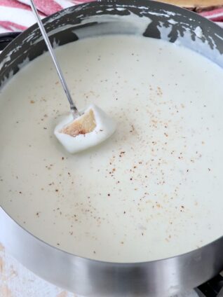 piece of bread dipped into cheese fondue in pot