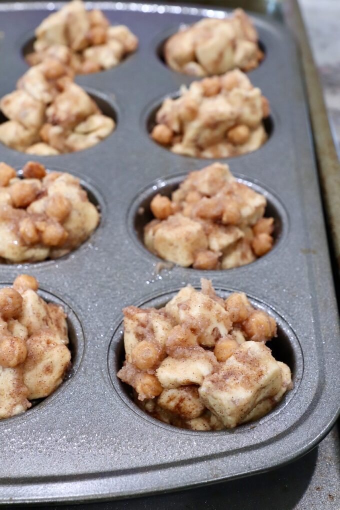 diced up cinnamon rolls tossed with melted butter, cinnamon, sugar and caramel bits, in a muffin pan