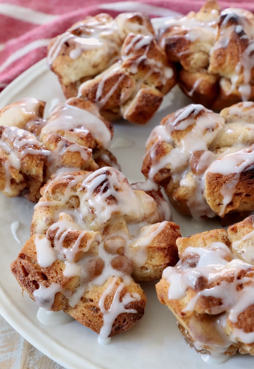 pull apart cinnamon rolls drizzled with cream cheese icing on plate