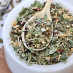dried herbs and spices mixed together in a small white bowl with a spoon