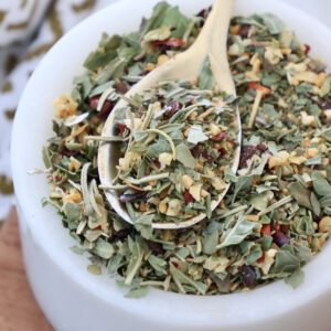 dried herbs and spices mixed together in a small white bowl with a spoon
