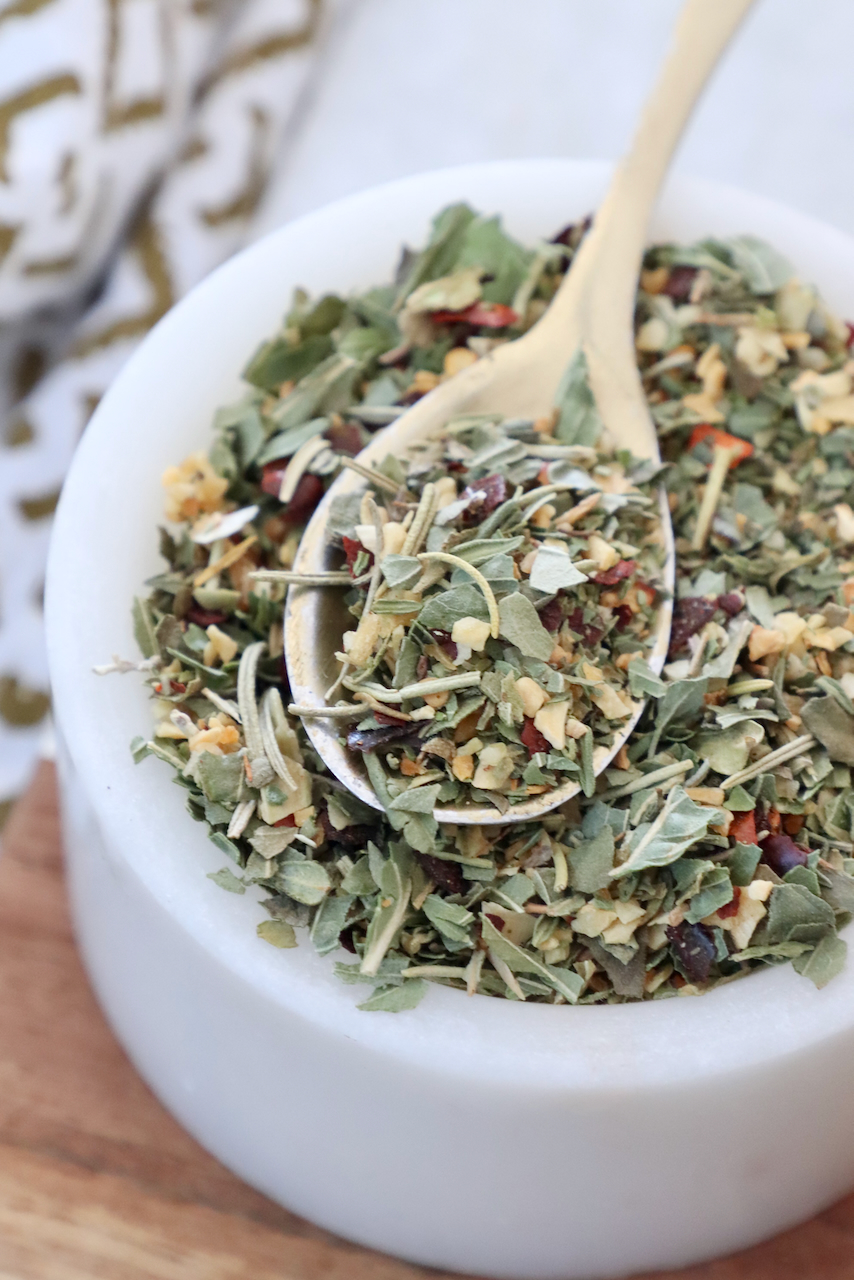 dried herbs and spices mixed together in a bowl with a spoon