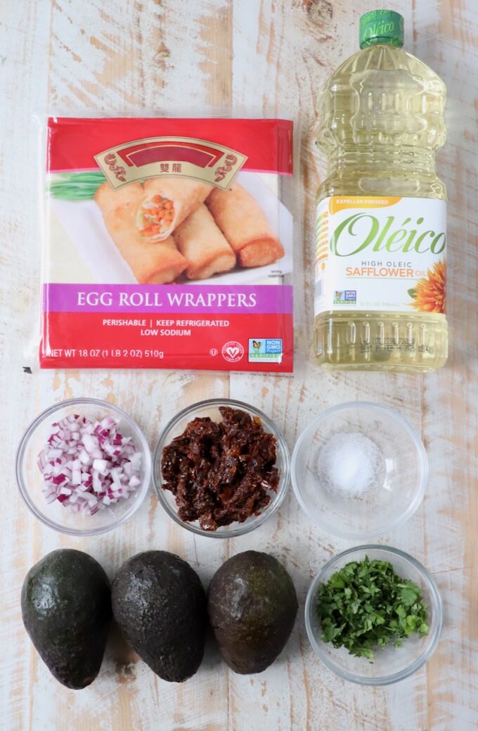 ingredients for avocado egg rolls on white wood board