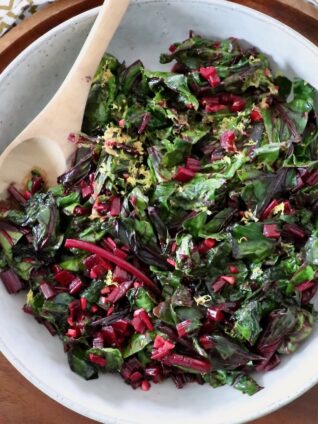 sauteed beet greens in bowl with wooden spoon