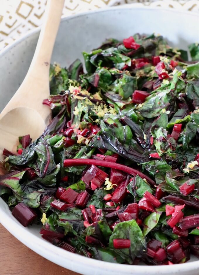 sauteed beet greens in a bowl with a wooden spoon