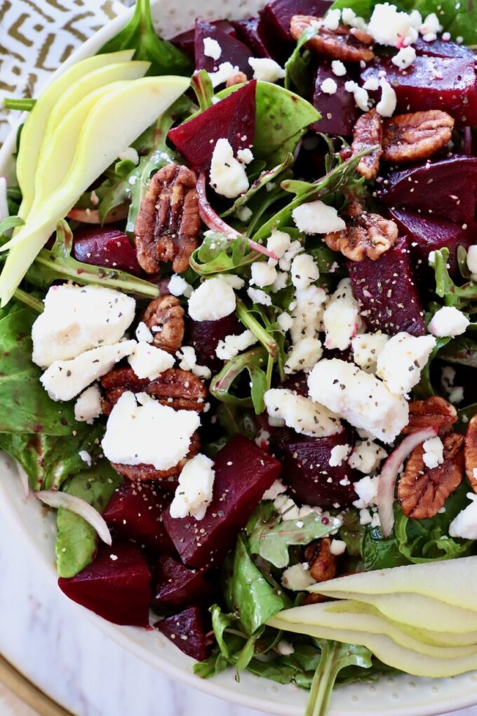 salad in bowl topped with roasted beets and feta cheese crumbles