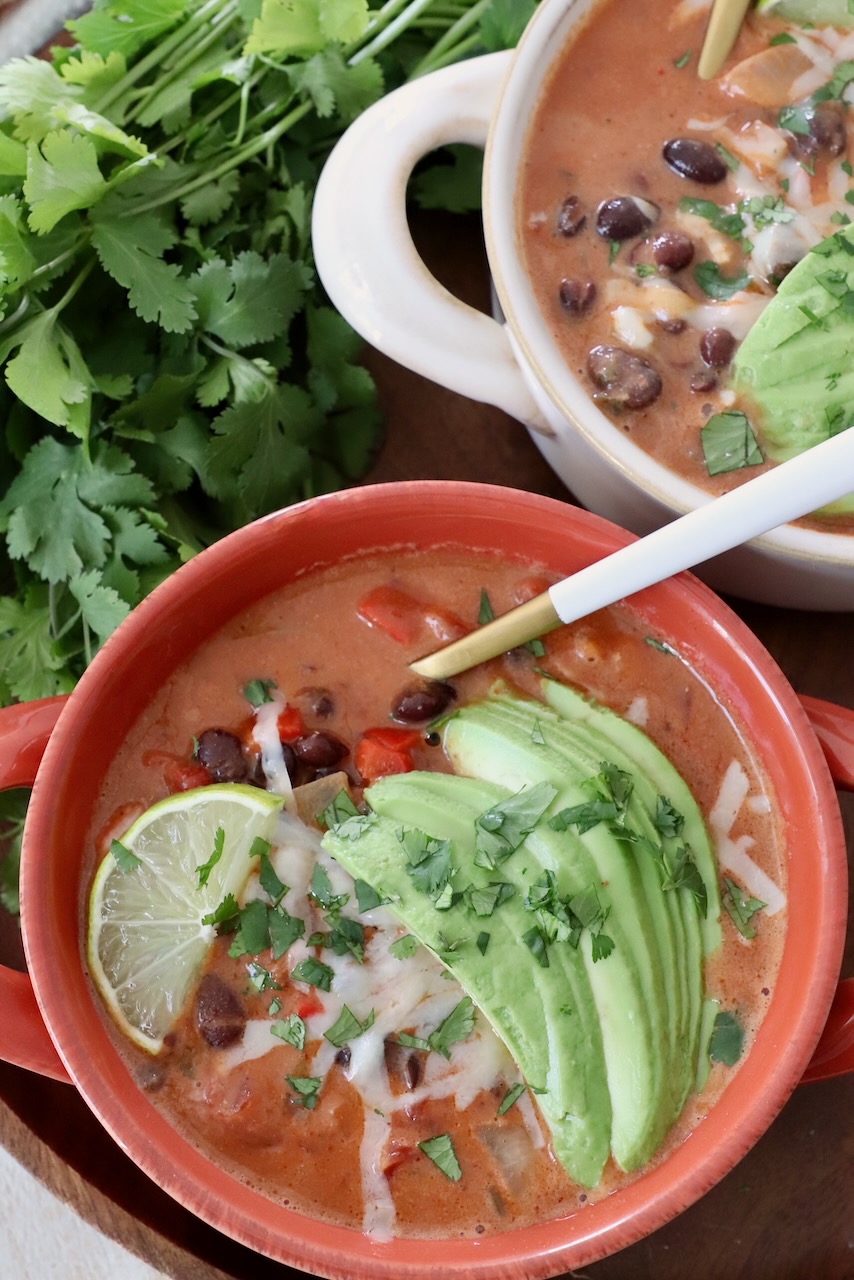 black bean soup in bowl with spoon, topped with sliced avocado