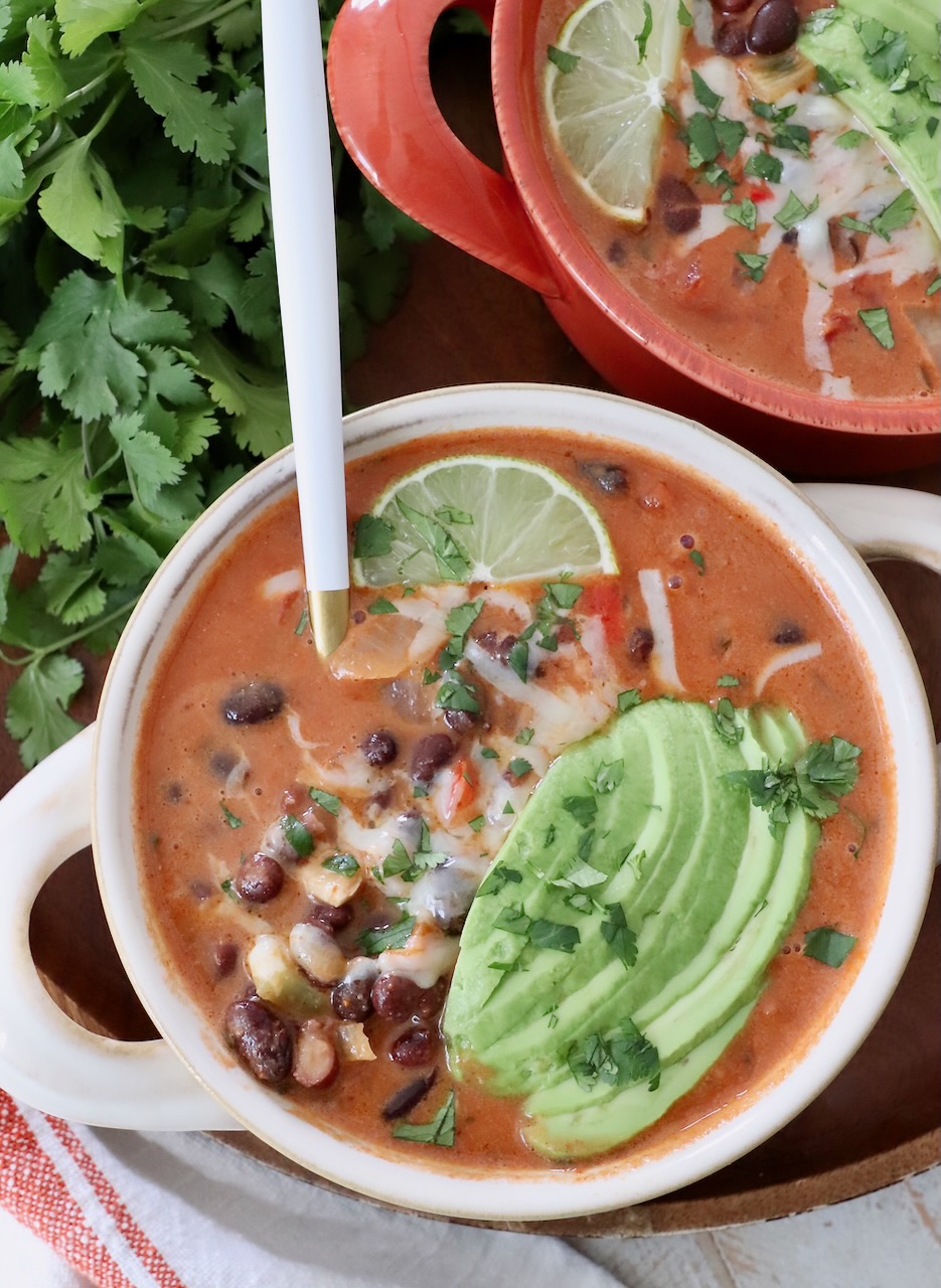 black bean soup in bowl with spoon, topped with sliced avocado