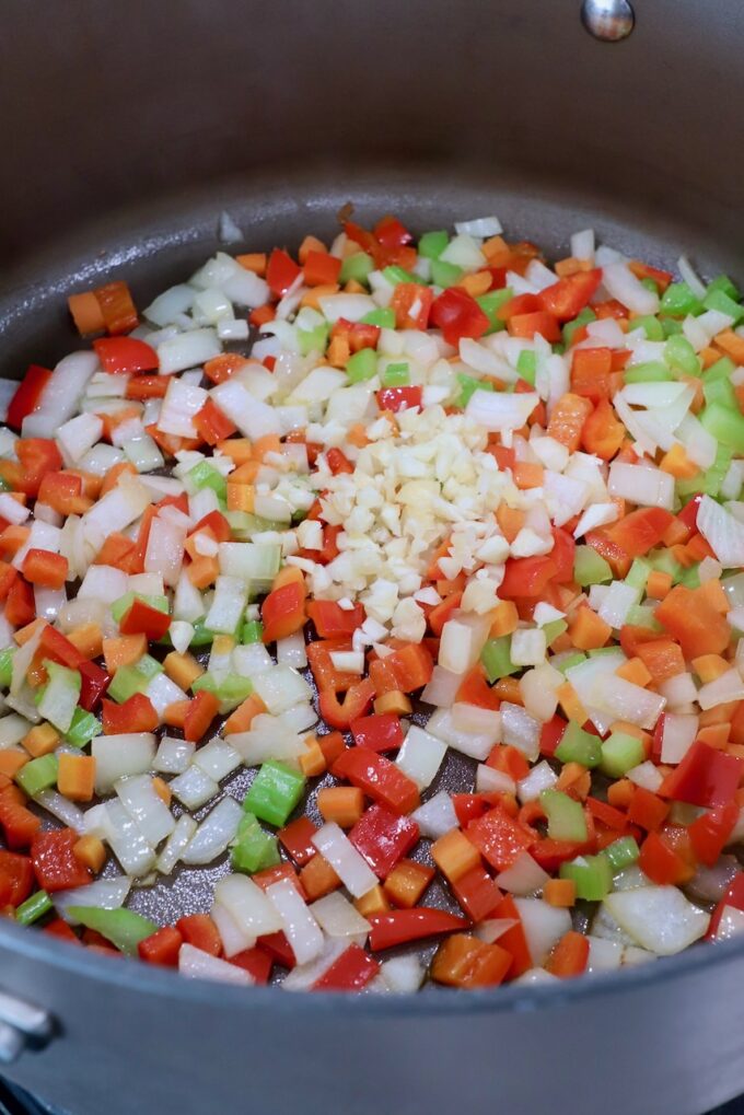 diced onions, carrots, red bell peppers, garlic and celery in large pot on stove