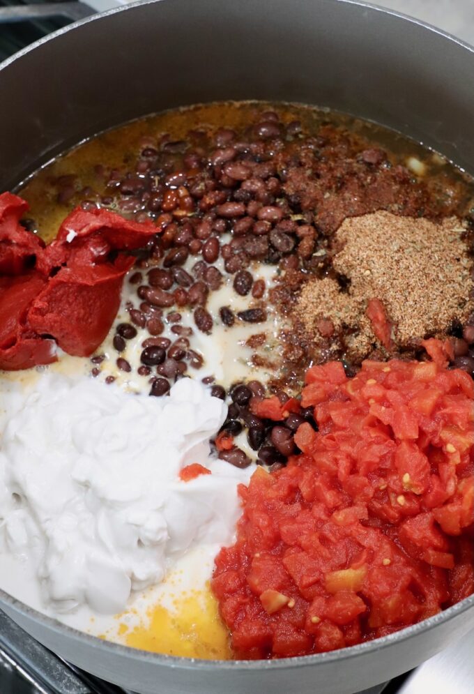 black beans in pot on the stove with coconut milk, diced tomatoes, tomato paste and spices