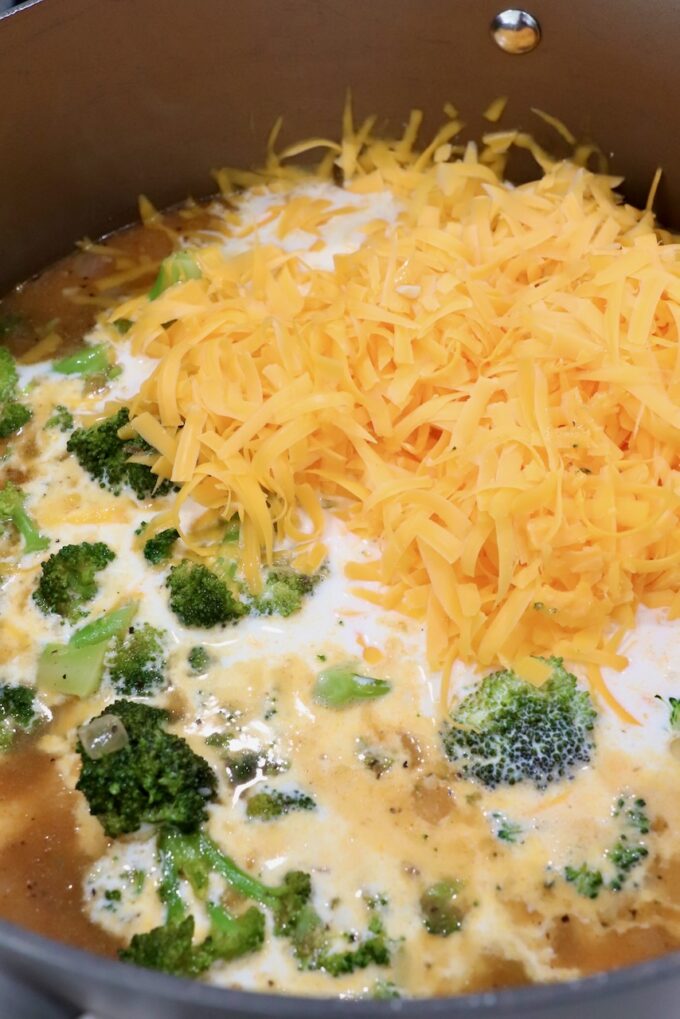shredded cheese and half and half in pot with broccoli and seasoned chicken broth