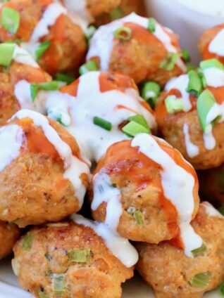 buffalo chicken meatballs on plate, topped with a drizzle of buffalo sauce and blue cheese dressing