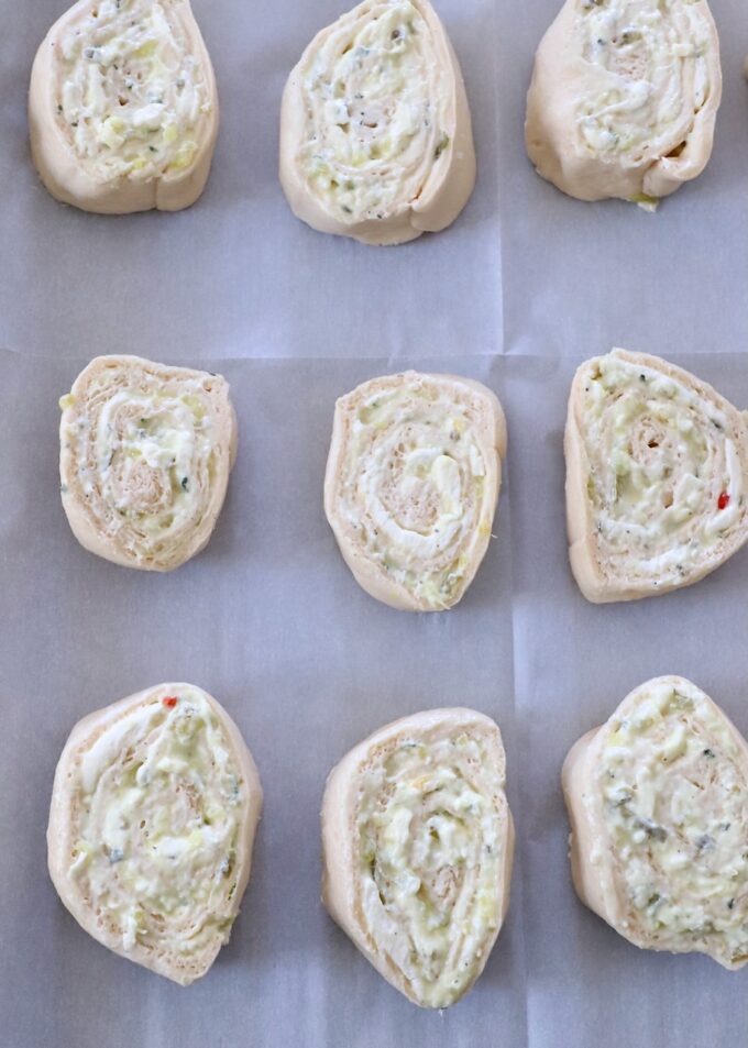 uncooked creamy pickle rolls on parchment-lined baking sheet