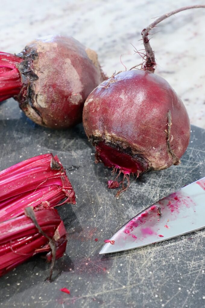 raw beets on cutting board with the stems cut off