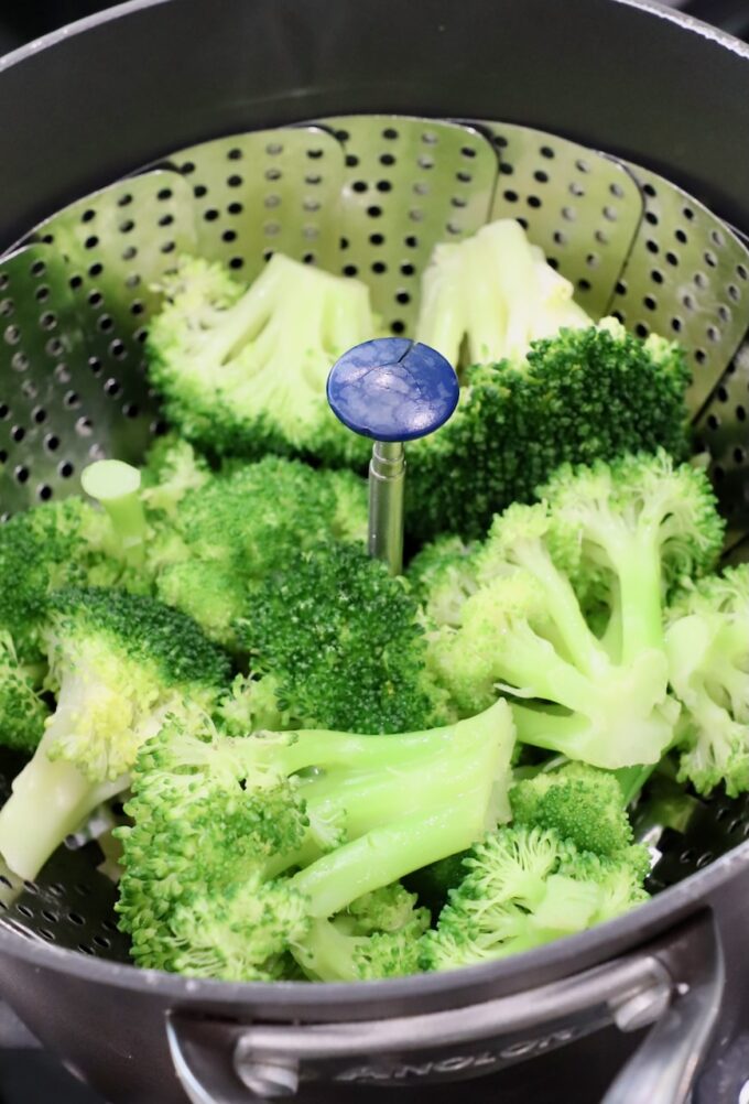 steamed broccoli in steamer basket in pot