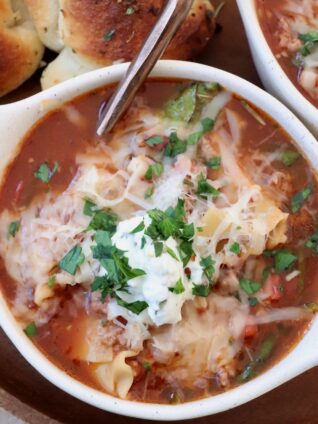 lasagna soup, topped with cheese, in bowl with spoon