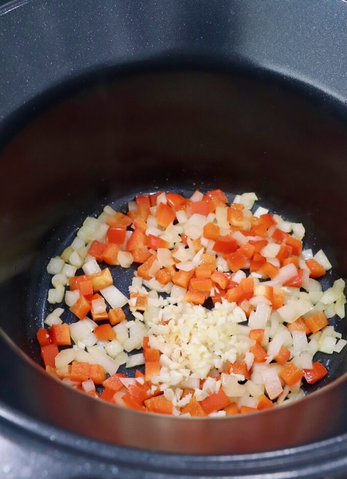 diced bell pepper, onion and garlic in pot on the stove