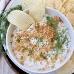 pickle dip in bowl topped with toasted breadcrumbs, with chips in the dip