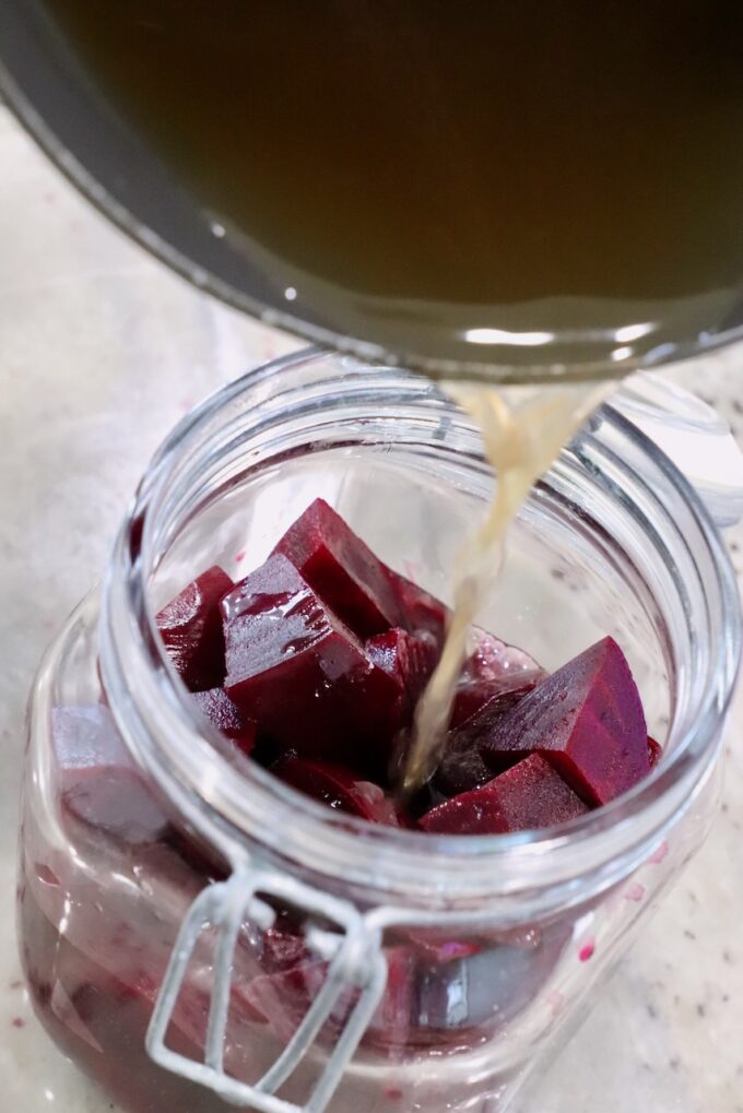 pickling liquid poured over steamed beets in a large jar