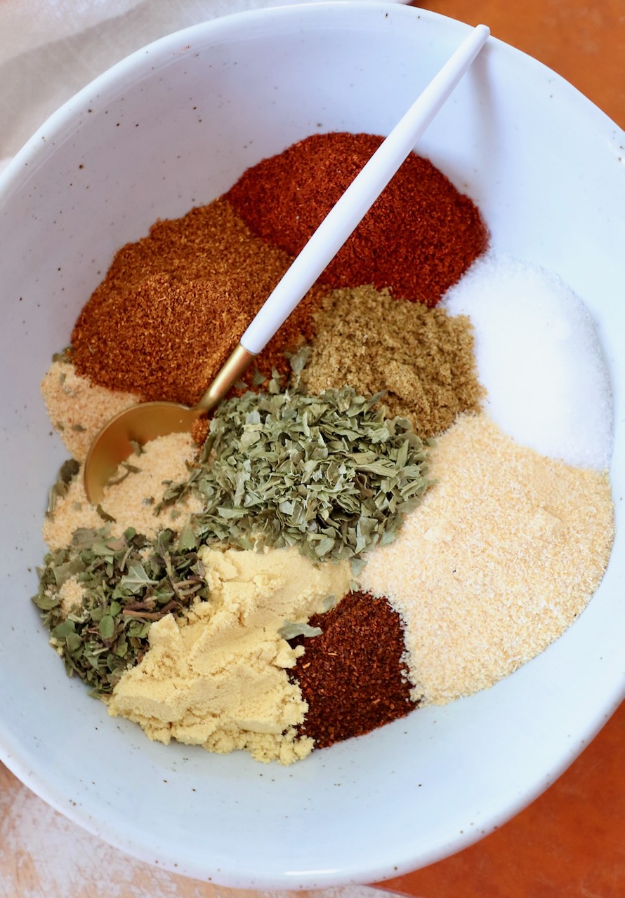 dried herbs and spices separated in bowl with spoon