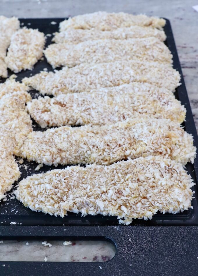 breaded chicken strips on cutting board