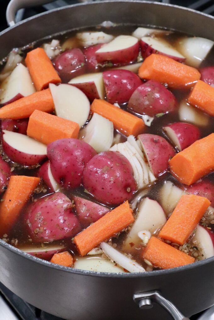 carrots, onions and red potatoes in beef broth in dutch oven