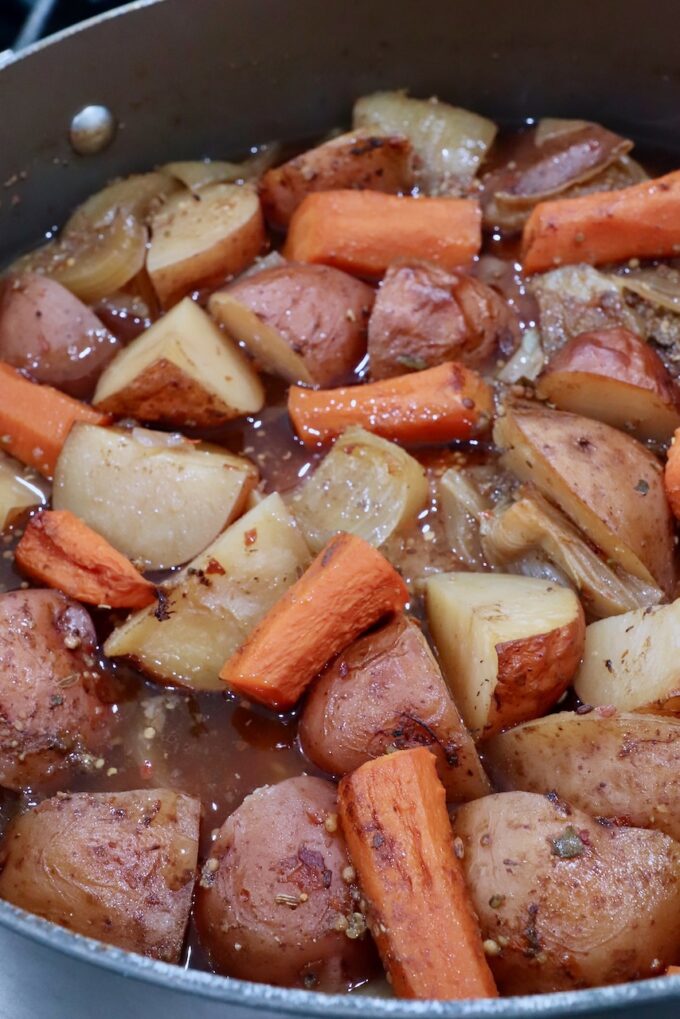 cooked potatoes, carrots and onions with a corned beef brisket in beef broth in a dutch oven