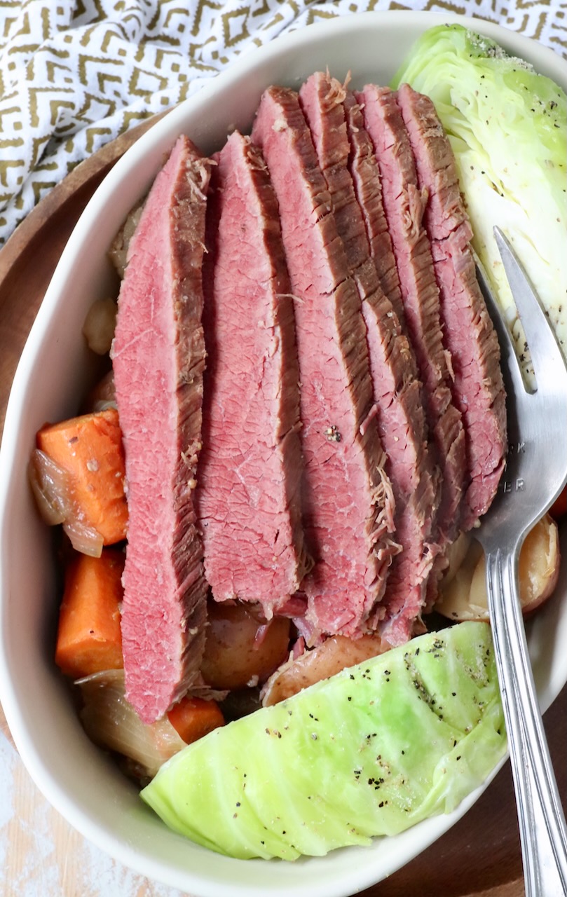 sliced corned beef in large serving dish with cabbage and carrots