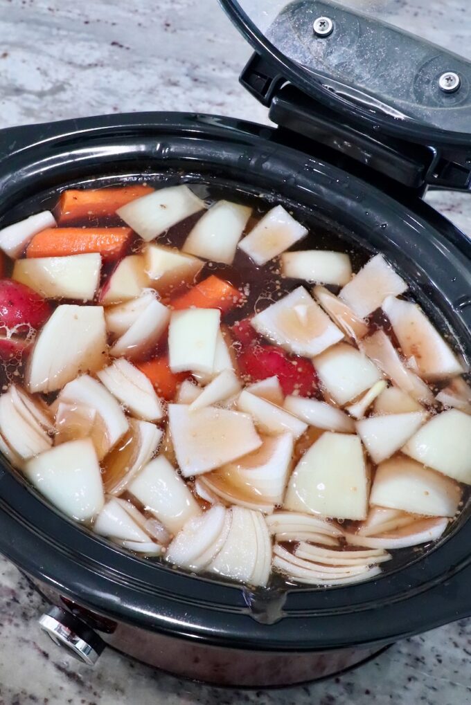 vegetables in crock pot with beef broth and brisket