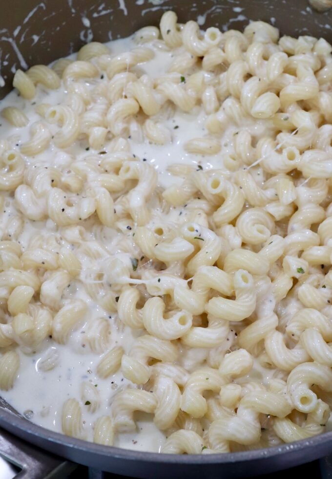 creamy cheese sauce and cooked cavatappi noodles in saucepan
