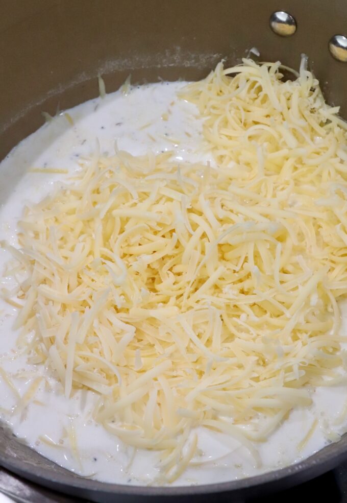 grated cheese in creamy sauce in saucepan