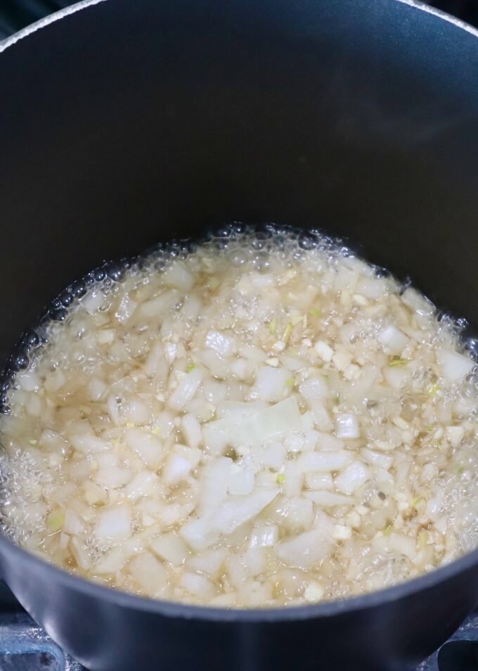 diced onions simmering in whiskey in a saucepan on the stove