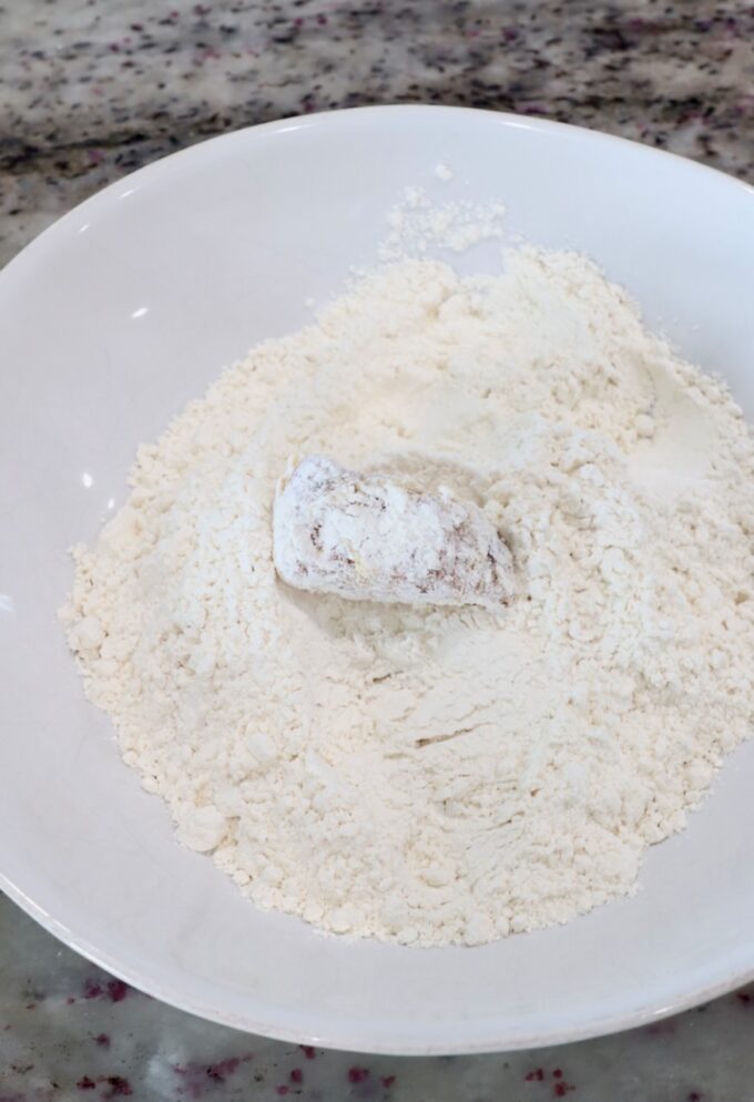 piece of chicken covered in flour in bowl