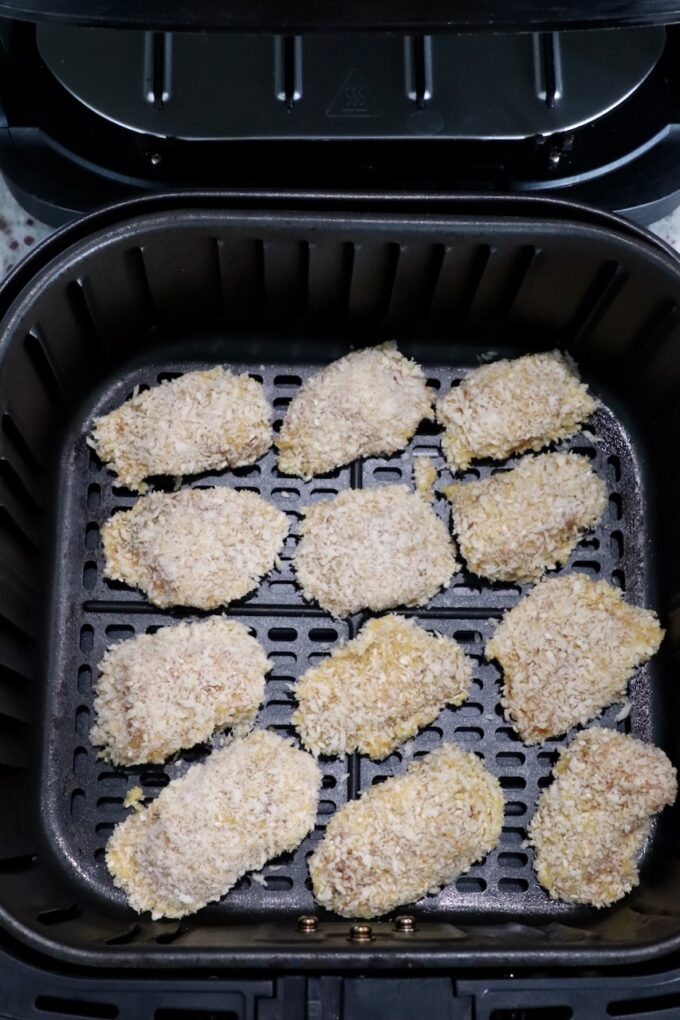 uncooked breaded chicken strips in an air fryer basket