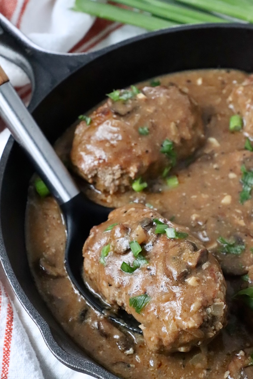salisbury steak lifted up out of skillet with serving sppon