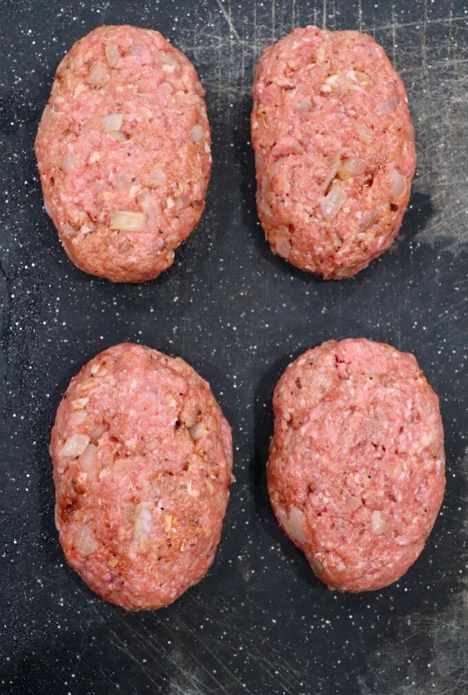 four beef patties on cutting board