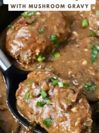 cooked beef patties in gravy in a pan with a serving spoon