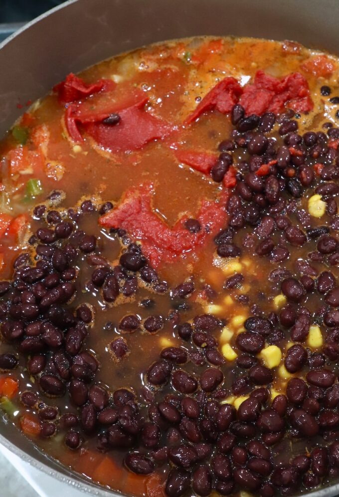 black beans, corn, diced vegetables, and chicken broth in pot on the stove