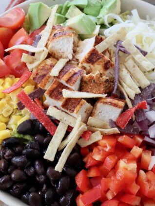 salad in bowl topped with black beans, corn and diced grilled chicken