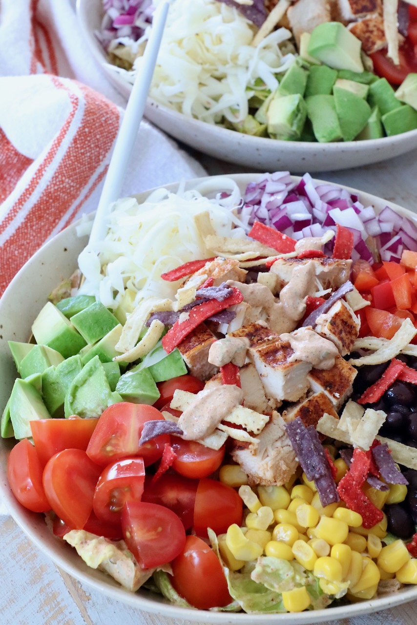 salad in bowl topped with chicken and creamy dressing