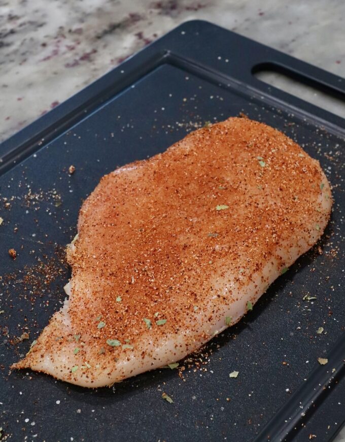 seasoned chicken breast on cutting board