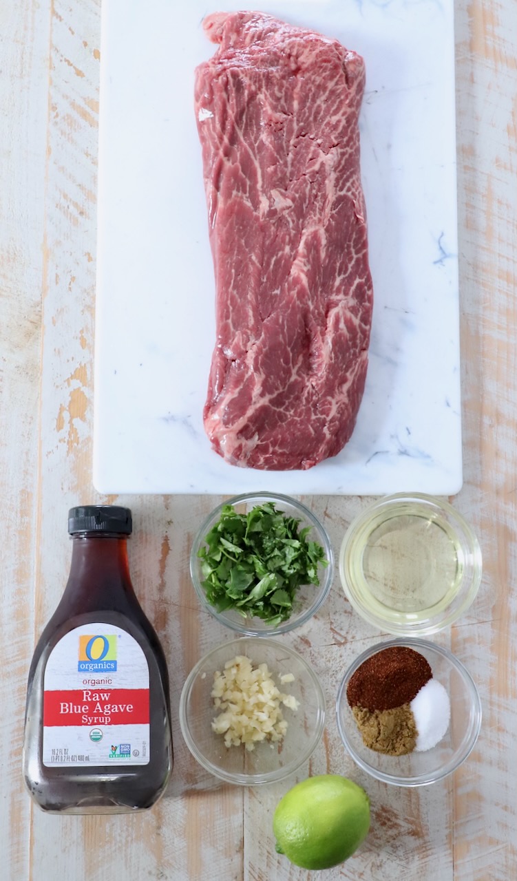 flat iron steak and marinade ingredients on white wood board