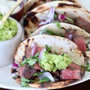 steak tacos topped with guacamole on plate