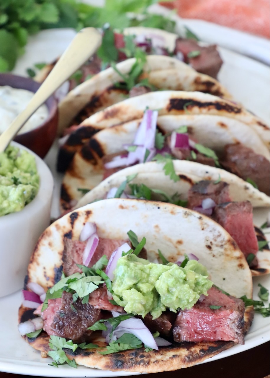 steak tacos on plate topped with guacamole