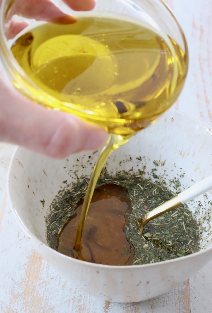 oil poured into bowl with vinegar and herbs