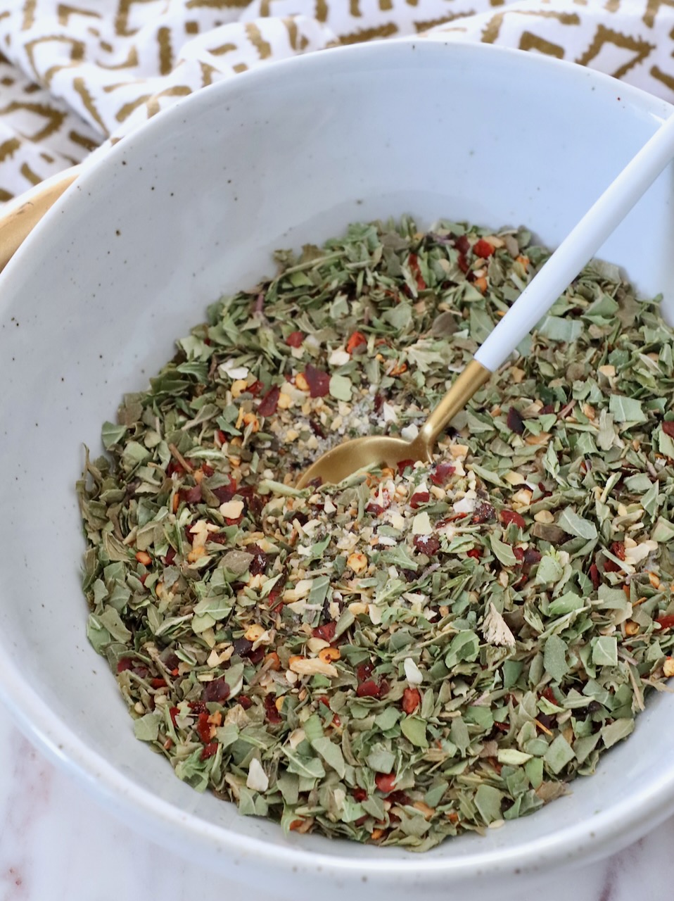 herbs and spices combined in bowl with small spoon