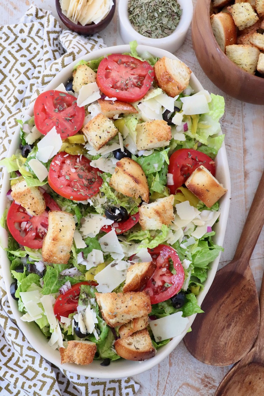 salad in serving dish topped with croutons and sliced tomatoes